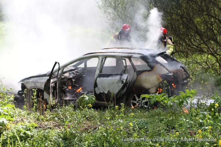 Auto in brand langs dijk in Wijdewormer